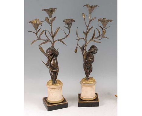 A pair of late 19th century French bronze and gilt bronze figural candelabra, the floral scroll branch arms (one missing) hel