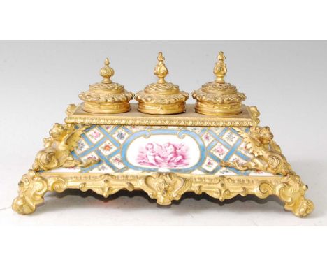 A 19th century French gilt bronze and porcelain inset encrier, having triple finial topped hinged inkwells over a porcelain p