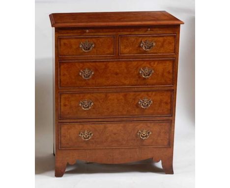 A walnut chest in the early 18th century style, having a rectangular moulded top with feather banding above a brushing and tw
