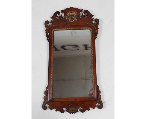 *An 18th century walnut and parcel gilt wall mirror, in the Chippendale style, having fret carved frieze and apron, 95 x 50cm