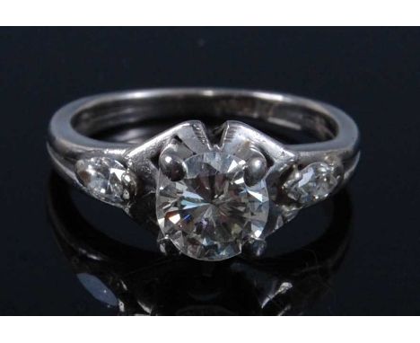 A white metal diamond single solitaire ring, featuring a round brilliant cut diamond in a four-claw setting, within a triangu
