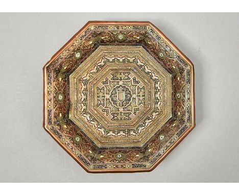 A MIDDLE EASTERN OCTAGONAL EMBOSSED AND ENAMELLED BRASS DISH, EARLY 20TH C, ON ASSOCIATED EBONISED WOOD STAND AND FOUR BRASS 