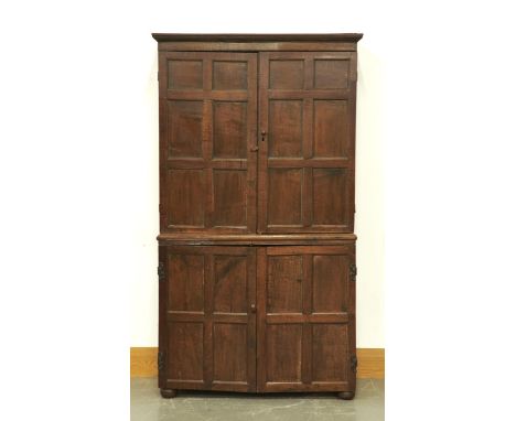 AN OLD REPRODUCTION OAK CUPBOARD IN LATE 17TH C STYLE, THE CORNICE ABOVE A PAIR OF SIX PANEL DOORS, THE BASE ENCLOSED BY FURT