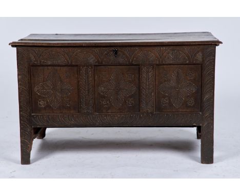 A LATE 17TH C OAK BLANKET CHEST, THE PLANK TOP WITH MOULDED LIP ABOVE CARVED FRIEZE AND THREE PANEL FRONT, FOLIATE CARVED ABO