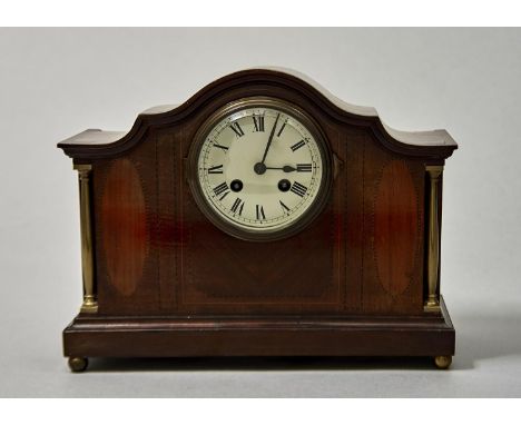 AN EDWARDIAN MAHOGANY MANTEL CLOCK OF SWEPT ARCHED FORM, INLAID WITH BOXWOOD, BARBER POLE AND PARQUETRY STRINGING, THE CREAM 