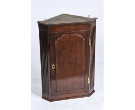 A GEORGE II OAK HANGING CORNER CUPBOARD, C1850, SINGLE DOOR WITH SHAPED RAISED FIELDED PANEL FLANKED BY FLUTED ANGLES, BRASS 