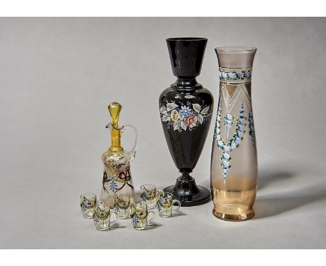 A FRENCH ENAMELLED GLASS LIQUER SET, C1910, DECORATED WITH FESTOONS AND FLOWERS, EWER AND STOPPER 24CM H, AN ENAMELLED BLACK 