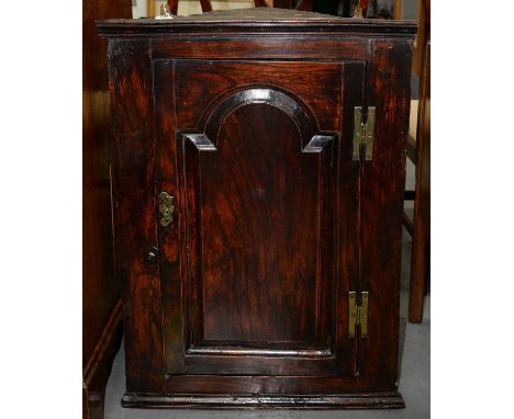 A GEORGE III ELM HANGING CORNER CUPBOARD, C1780, FITTED WITH TWO SHELVES ENCLOSED BY A DOOR WITH RAISED AND FIELDED BREAK ARC