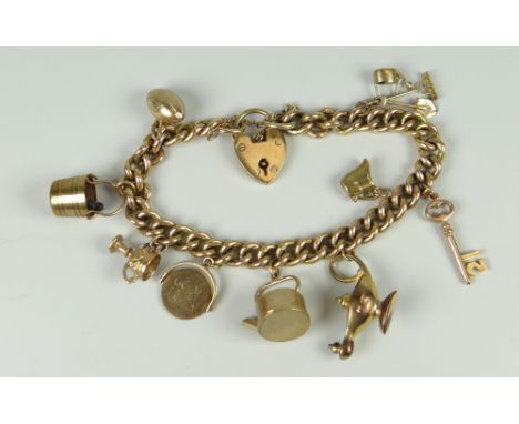 9CT GOLD CURB LINK CHARM BRACELET with heart shaped padlock & assorted charms to include genie lamp, tools, rugby ball, troph