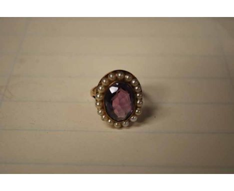 9CT GOLD DRESS RING WITH OVAL AMETHYST TYPE STONE WITHIN A BORDER OF SEED PEARLS 5.7G 