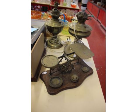 A large Victorian brass postal scales with six brass weights and two brass table lamps (oil conversions, sold as parts)