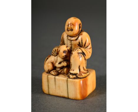Sehr altes Elfenbein Netsuke "Mann mit Hund auf Sockel sitzend", bernsteinfarbene Patina, Japan um 1700/1720, H. 4,2cm, Prove