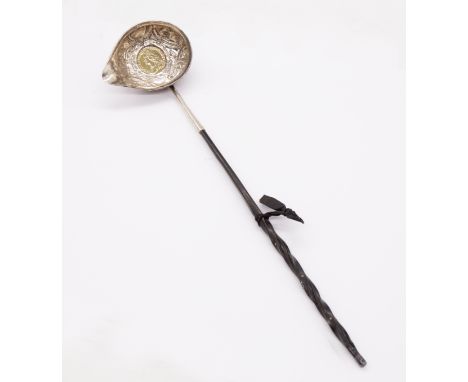 A mid 18th Century white metal toddy ladle, the ornate body inset with a George II silver gilt shilling dated 1758, ebonised 