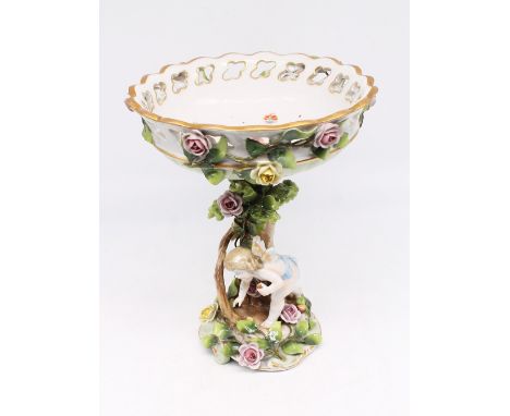 An early 20th century German porcelain tall comport with putti, floral and tree trunk designed base and stem, holding vines a