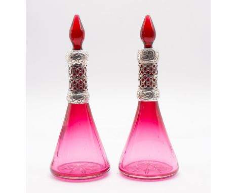 A pair of Edwardian silver mounted ruby glass conical shaped large scent bottles and stoppers, the silver collars with raised