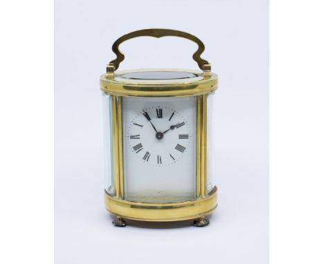 An early 20th Century gilt metal mounted oval shaped carriage clock, white enamel dial with Roman numerals, with key&nbsp;