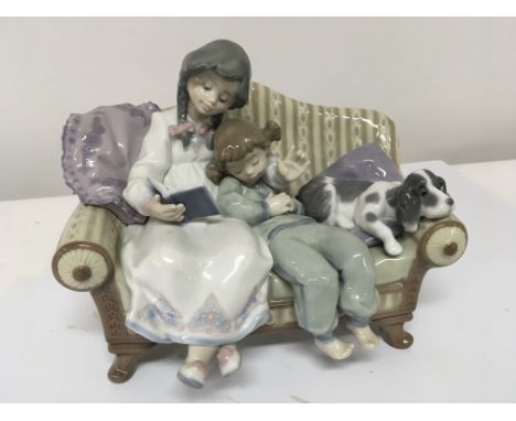 A good sized Lladro figure group of children seated on a sofa with a dog 23cm long no obvious damage or restoration.