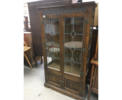 An oak display cabinet with lead light glazed doors glass shelfs above linen fold cupboard doors. Height 156cm width 88cm