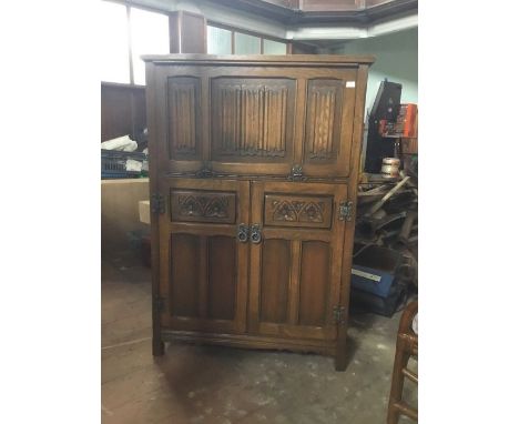 An Old Charm oak drinks cabinet, 3 panels of linenfold to upper hand which pulls open to reveal and morph into a mirror backe