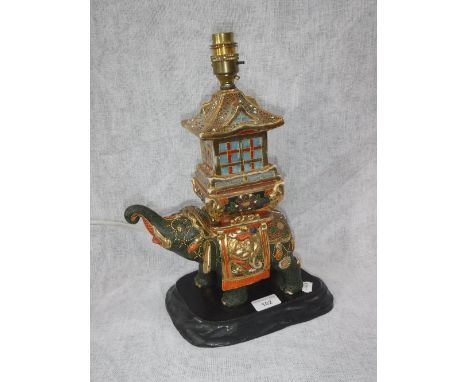 AN ORIENTAL CERAMIC TABLE LAMP in the form of an elephant, on a wooden base
