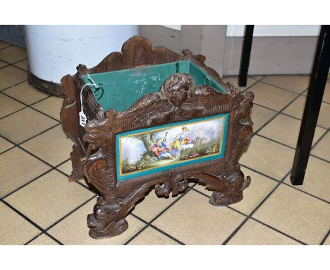 A 19TH CENTURY BLACK FOREST WOODEN PLANTER, with porcelain panel depicting a male figure playing the bag pipes to entertain a