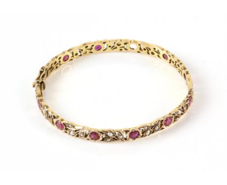 Antique floral cut out bangle, set with round cut rubies and seed pearls, mounted in 9 ct yellow gold with concealed clasp an