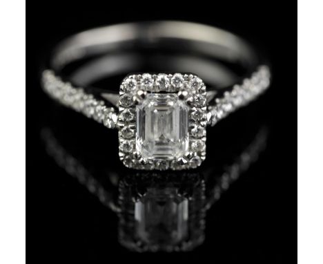 Modern diamond ring, central emerald cut diamond, with a W.G.I certificate stating a weight of 0.70 carats, with a border of 