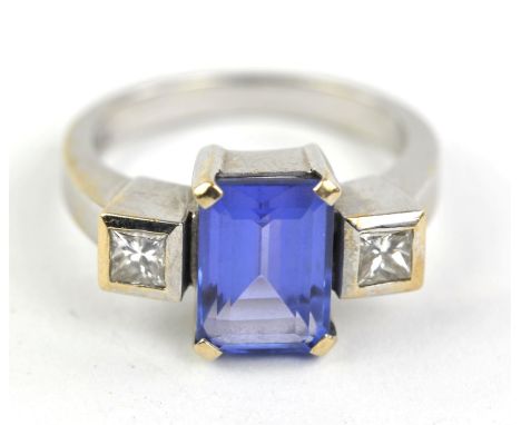 Tanzanite and diamond three stone ring, with central claw set emerald cut tanzanite weighing an estimated 2.85 carats, flanke