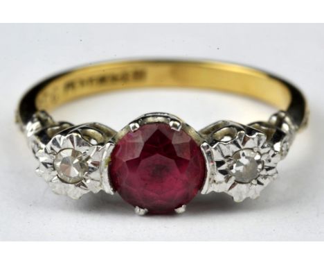 A synthetic ruby and diamond three stone ring, with a central round cut synthetic ruby and an illusion set single cut diamond