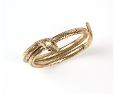 A wrap around snake bangle, flexible snake gas pipe bangle with ribbed body and engraved head with ruby eyes, in 9 ct hallmar