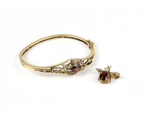A garnet and seed pearl hinged bangle, set with central oval cut garnet, with seed pearl set openwork designs, in 14 ct, toge
