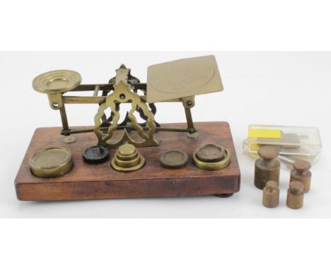 A set of brass 'Inland Letter Post' postal scales mounted on an oak plinth, with a quantity of various weights