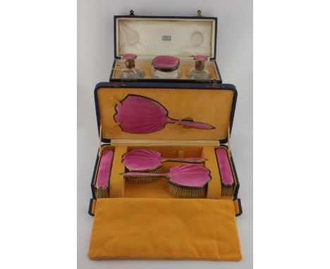 Silver & pink enamel dressing table set, comprising four brushes, hand mirror, two silver topped bottles (one lid detached at