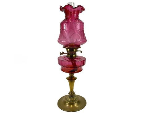 A Victorian cranberry glass oil lamp, With an etched cranberry shade, on a brass base, height 62cm.