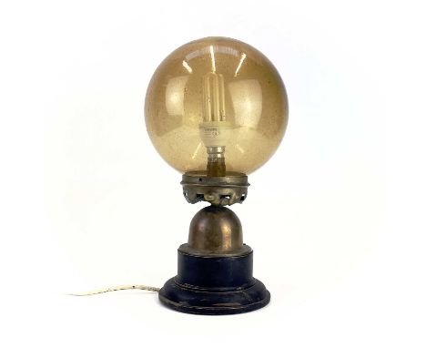 An Art Deco table lamp. With amber glass globular shade, the brass base raised on an ebonised wood socle. Height 36cm.