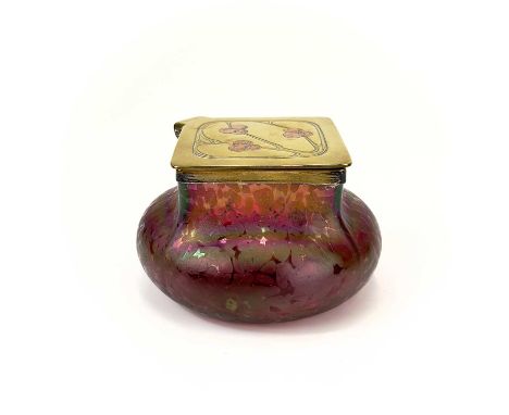A Loetz type ruby iridescent glass inkwell. The lozenge shaped brass cover inset with copper berries, height 6.5cm, diameter 