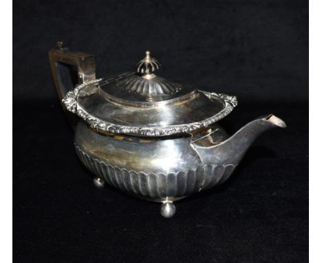 A LATE VICTORIAN SILVER TEAPOT With ebonised handle and lid top knob, on four ball feet, fluting to lower body and scroll dec