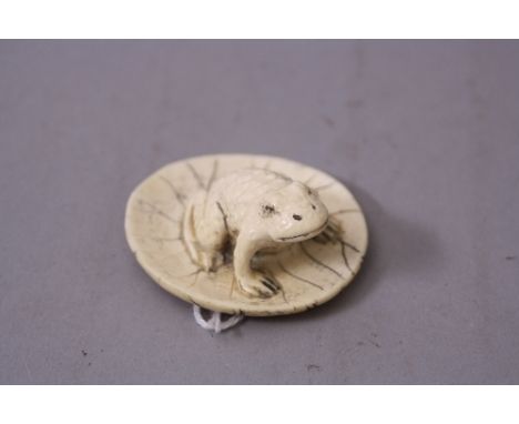 AN EDWARDIAN IVORY NETSUKE OF A TOAD ON A LILY PAD