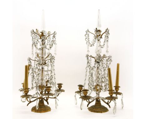A pair of brassed metal candelabra, with five arms and prismatic drops, 66cm high