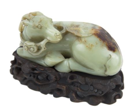 A CHINESE CELADON AND RUSSET JADE CARVING OF A RECLINING DEERthe recumbent deer is carved with its head turned sharply backwa