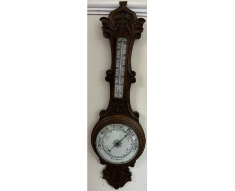 An oak cased aneroid barometer, with a white enamel dial and mercury thermometer