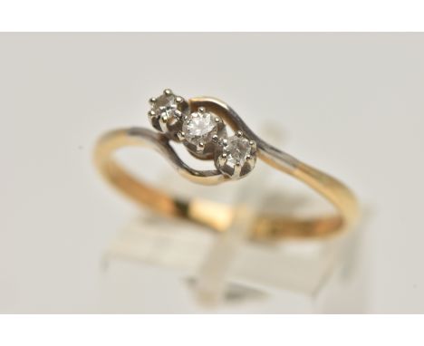 A YELLOW METAL THREE STONE DIAMOND RING, of a cross over design, set with a central round brilliant cut diamond, flanked with