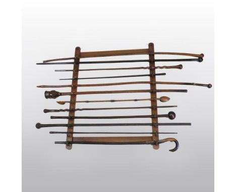 A 19th century mahogany wall rack, mounted with brass hooks and containing a collection of twelve various 19th century wooden