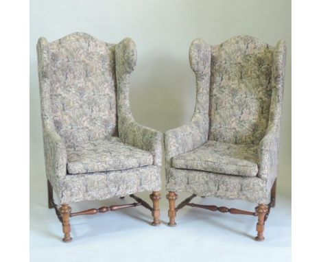 A pair of early 20th century tapestry upholstered wing back arm chairs, on turned walnut legs