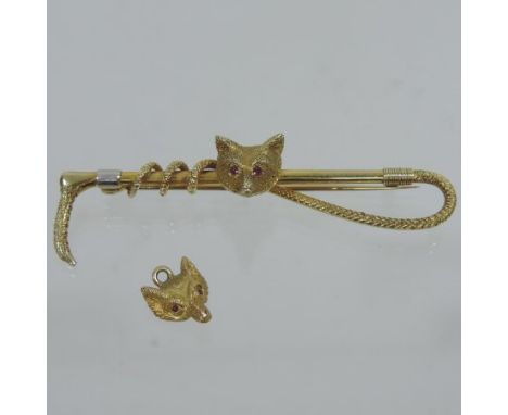 A gold and ruby set bar brooch of hunting interest, in the form of a foxes head, with ruby eyes set on a riding crop, marks r