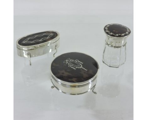 An early 20th century silver, tortoiseshell and pique decorated trinket jar, together with another, each of hinged shape on c