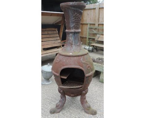 A cast iron garden stove on three scrolled feet, 148cm tall