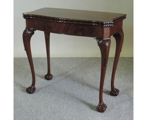 A 1920's carved mahogany folding serpentine card table, on claw and ball feet, 84cm
