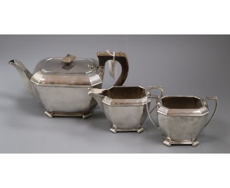 A matched silver three-piece tea service, of shaped rectangular form with reeded corners, handles and feet, comprising teapot