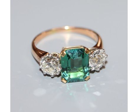 A yellow metal, green tourmaline and diamond set three stone ring, size M/N.